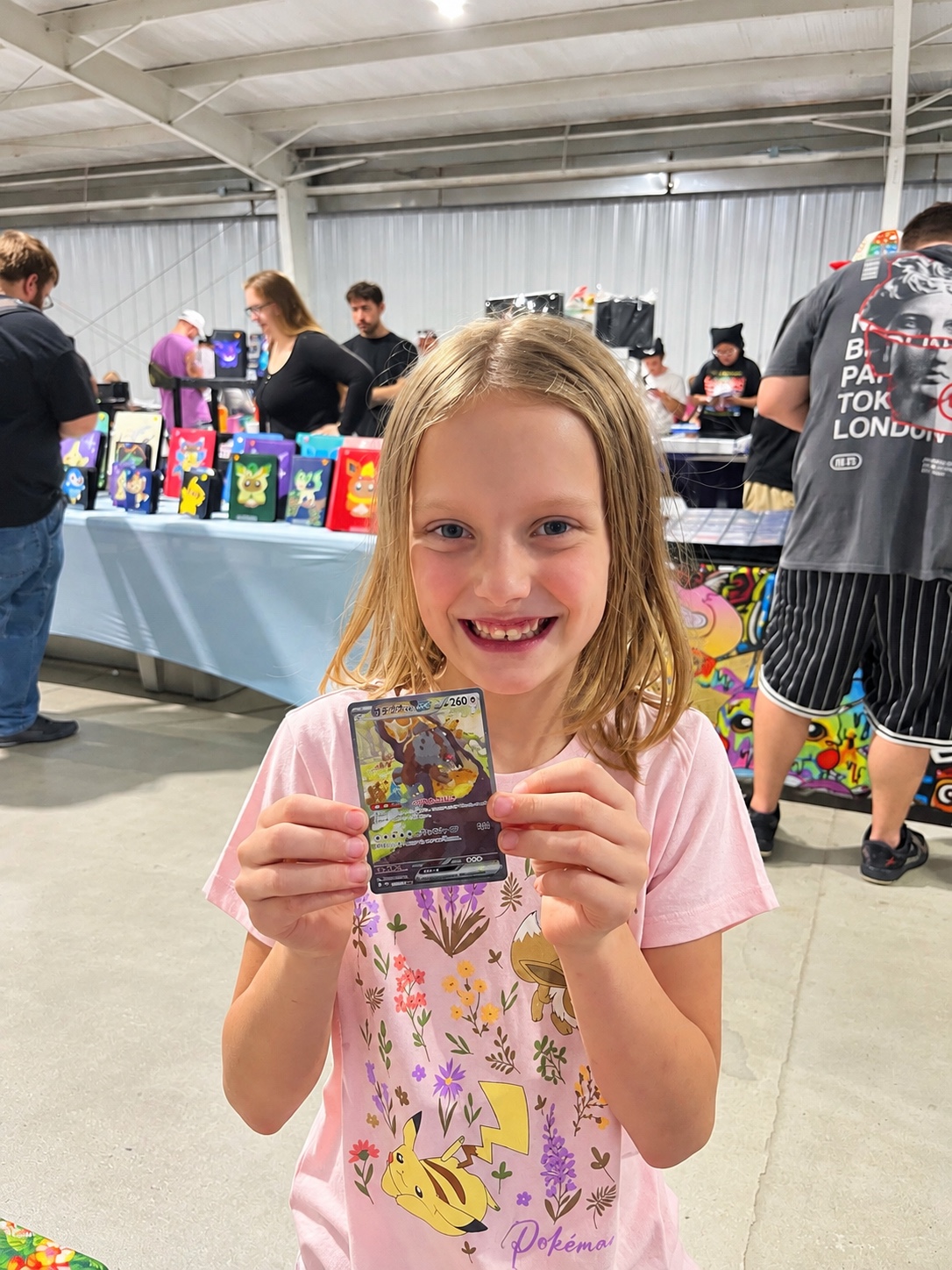 Young collector proudly holding a trading card at a card show